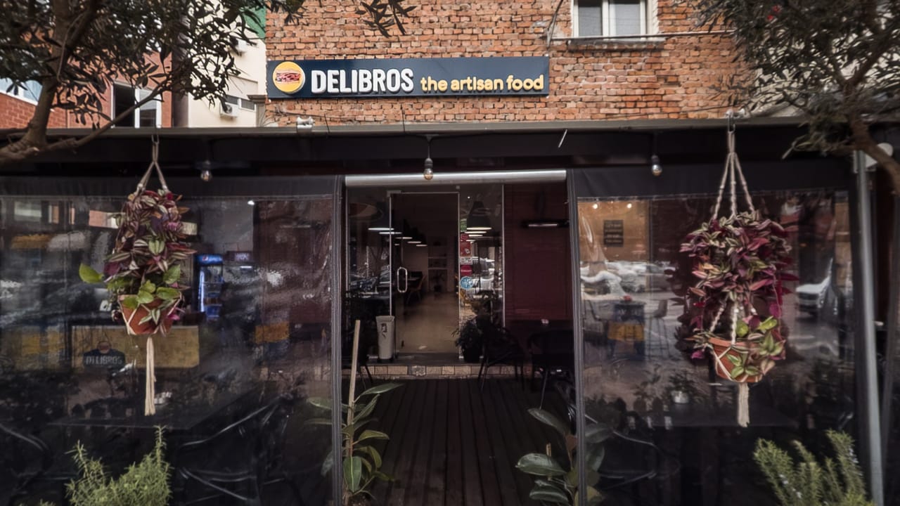 The frontage of Delibros at Komuna e Parisit, glazed and hung with plants