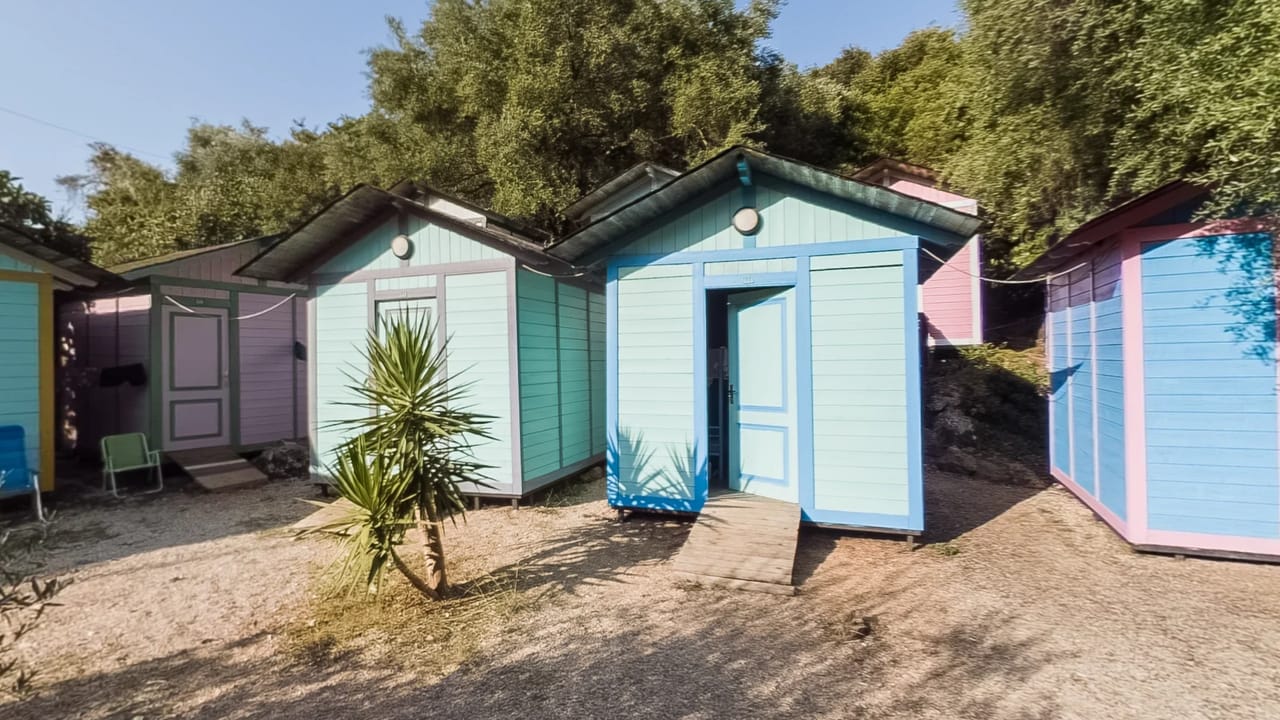 A row of painted timber bungalows under trees at Social Camp Jale